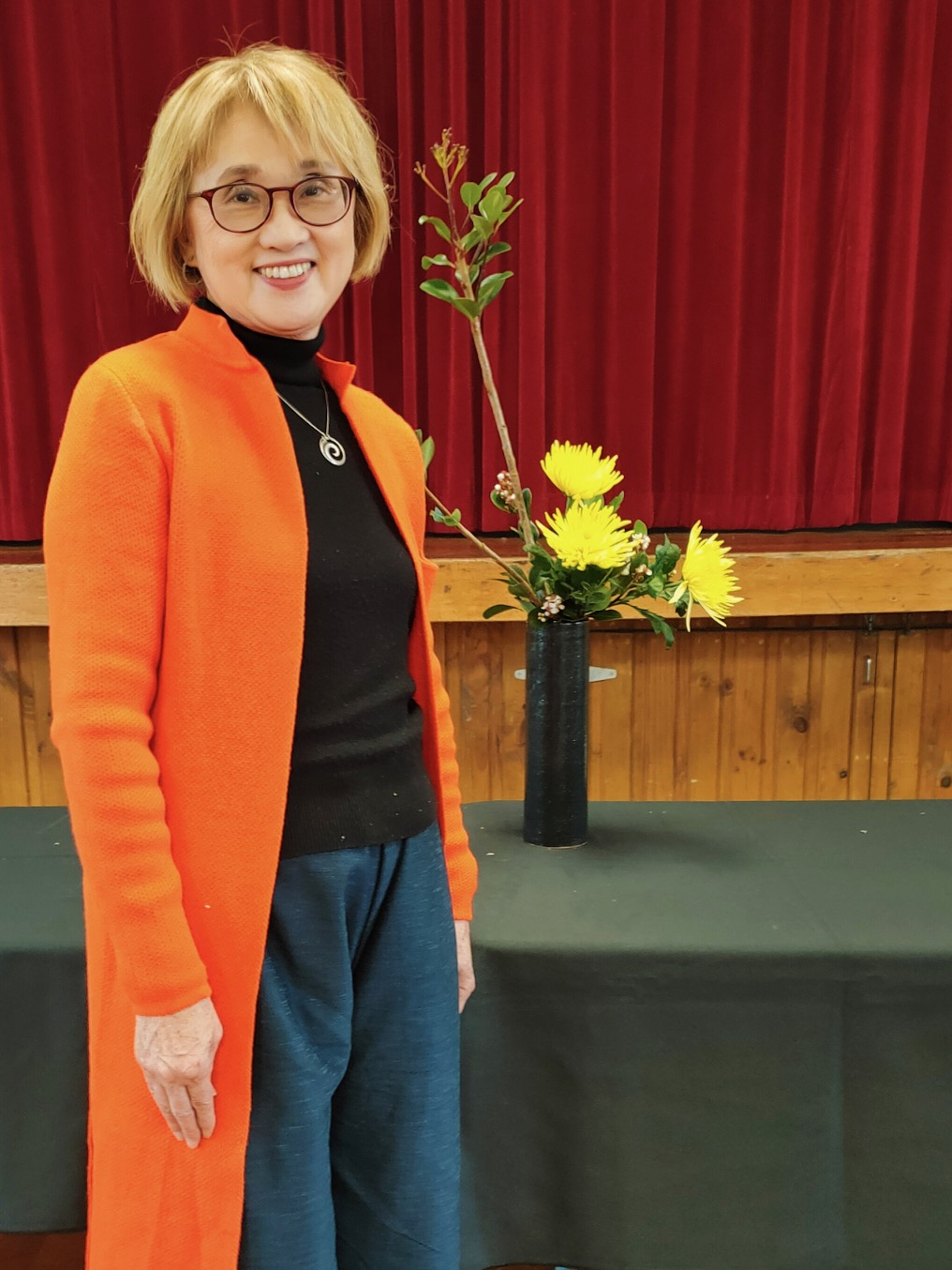 Ikebana instructor Tomoko Hirano standing beside her flower arrangement
